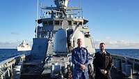 Zwei Männer in Uniform stehen auf einem grauen Marineschiff in der Ostsee.