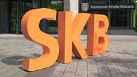 Orangefarbene Buchstabenskulpturen S, K und B