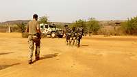 Zwei malische Soldaten ziehen einen verwundeten Soldaten in einen sicheren Bereich