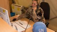 Eine Soldatin sitzt am Schreibtisch und telefoniert