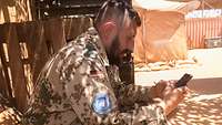 Ein Soldat schreibt auf seinem Mobiltelefon