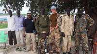 Ein deutscher Soldat steht mit mehreren südsudanesischen Personen unter einem Baum