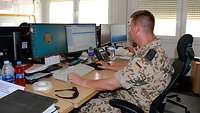 Ein Soldat sitzt am Schreibtisch und arbeitet am Computer