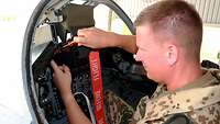 Ein Soldat sitzt im Cockpit eines Tornados und benutzt einen Schraubenzieher