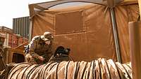 Ein Soldat in Mali der auf einen elektrischen Anschluss schaut.