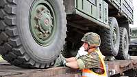 Ein Soldat schiebt einen Keil unter das Rad eines LKW.