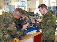 Zwei Soldaten schrauben an einem Triebwerk in einem Unterrichtsraum.