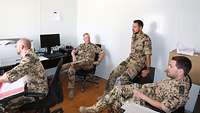 Vier Soldaten besprechen sich in einem Büro
