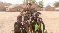 Ein Soldat mit Ausrüstung und eine Gruppe Kinder.