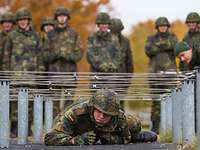 Soldat kriecht unter einem Hindernis durch