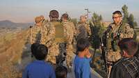 Soldaten und afghanische Kinder stehen auf einem Berg und blicken über Kabul