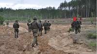 Soldaten bewegen sich in Formation im sandigen Gelände vorwärts