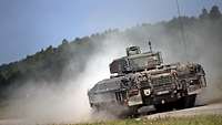 Full astern: A tank reverses in a plume of dust.