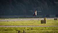 A LUH SAR helicopter flies over a field at low altitude.