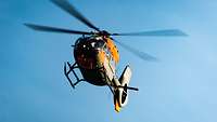 A rescue helicopter in flight under clear blue skies