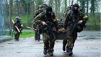 Several soldiers carry a heavy crate.