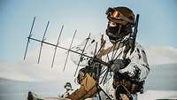 A soldier adjusts a radio antenna.