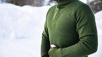 A soldier stands in the snow wearing a green, skin-tight, long-sleeve wool undershirt. 