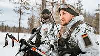 Two infantrymen in white camouflage crouch in the snow. 