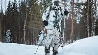 Three soldiers in snow camouflage move through snowy terrain in single file with their skis, poles and rifles.