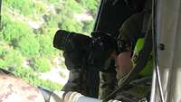 Eine Soldatin hält einen Fotoapparat in den Händen und sitzt in einem Helikopter 