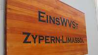 Ein Schild mit der Aufschrift Einsatzwehrverwaltungsstelle Zypern-Limassol ist an einer Wand angebracht