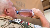 Ein Soldat trinkt aus einer Wasserflasche