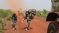 Ein malischer Soldat trägt einen Verwundeten auf den Schultern aus dem Gefahrenbereich. 