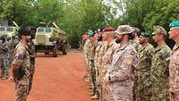 Zwei Soldaten stehen vor dem angetretenen internationalen Trainerteam