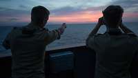 Zwei Soldaten schauen mit Ferngläsern auf das Meer und halten nach Schiffen ausschau