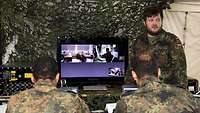 Ein Soldat steht vor einem Monitor und erklärt anderen Lehrgangsteilnehmern etwas