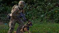 Hundeführer vom Objektschutzregiment bewaffnet und in Uniform mit seinem Diensthund.