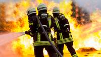 Drei Feuerwehrleute der Bundeswehr löschen lodernde Flammen