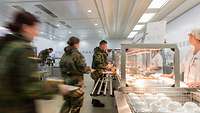 In einer Truppenküche der Bundeswehr stehen Soldaten an der Essenausgabe.