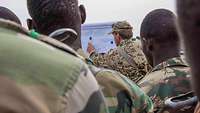 Deutscher Soldat erklärt nigirischen Soldaten den Ablauf der Übung an einem Flipchart