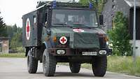 Ein Lastkraftwagen der Bundeswehr mit einem roten Kreuz vor weißem Hintergrund (dem Symbol des Sanitätsdienstes) auf der Seite.