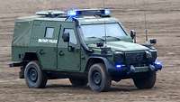Ein Militärfahrzeug mit Blaulicht bei schneller Fahrt im Gelände
