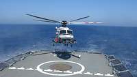 Ein Helikopter hebt vom Flugdeck eines Schiffes ab