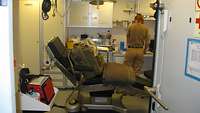 Eine Soldatin steht in einem Zimmer mit einem Krankenstuhl 